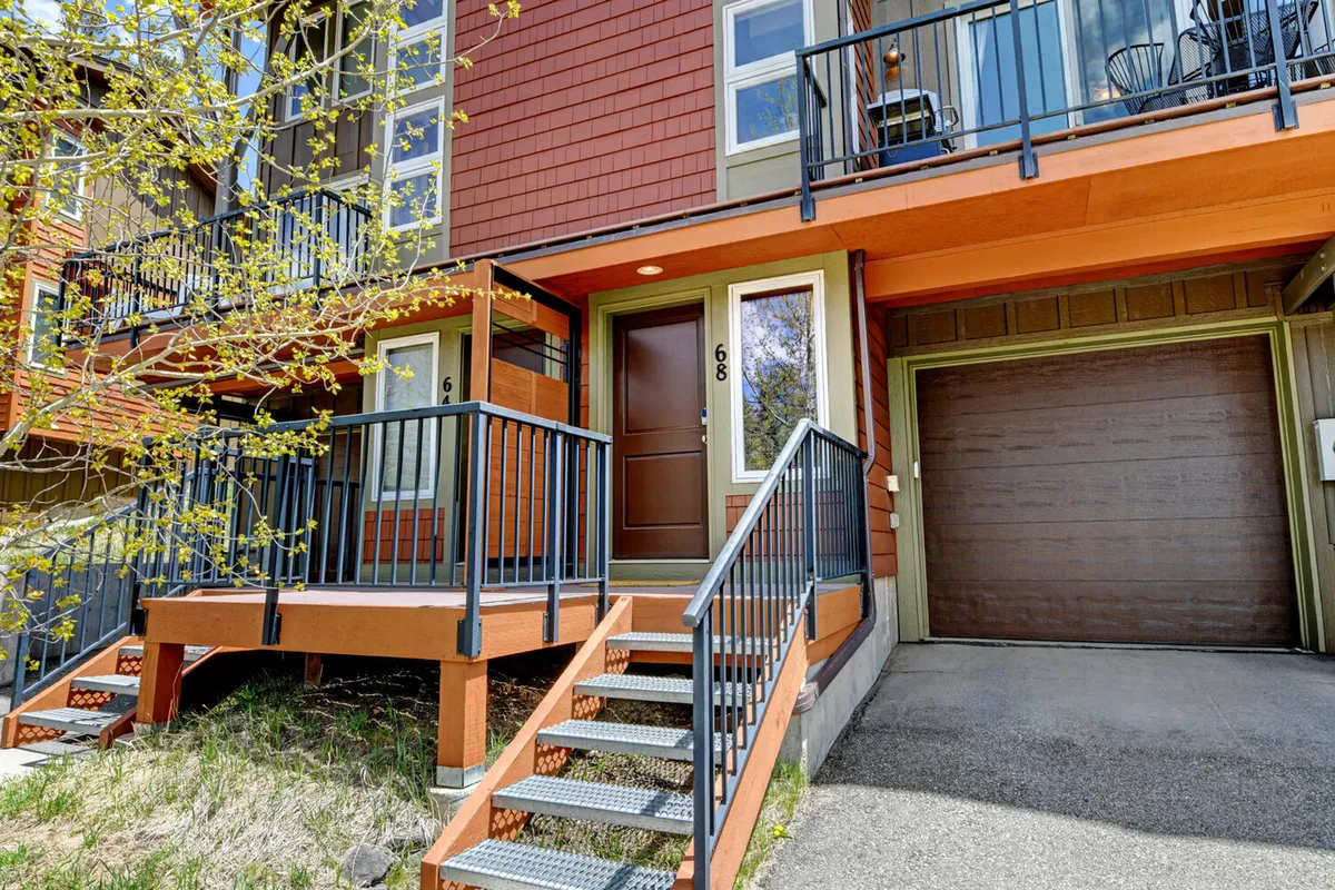 A welcoming view of the chalet’s front door, staircase, and balcony, suggesting easy access for guests and their pets. The front yard hints at opportunities for outdoor relaxation and play.