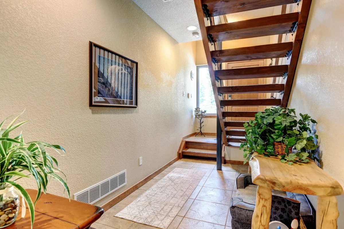 A welcoming view of a stylish staircase and large window framed by plants, offering a glimpse into the inviting interior ambiance of the chalet. The warm mood and thoughtful decor set the stage for luxury and comfort.
