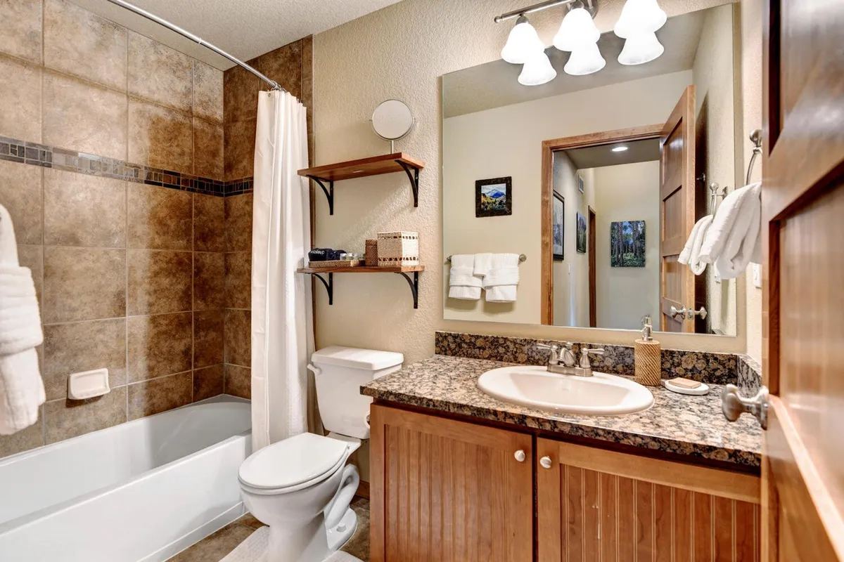 A bright and refreshing bathroom featuring a modern bathtub, vanity with a sink, mirror, and well-organized shelves stocked with premium toiletries. The atmosphere invites guests to relax and enjoy moments of self-care.
