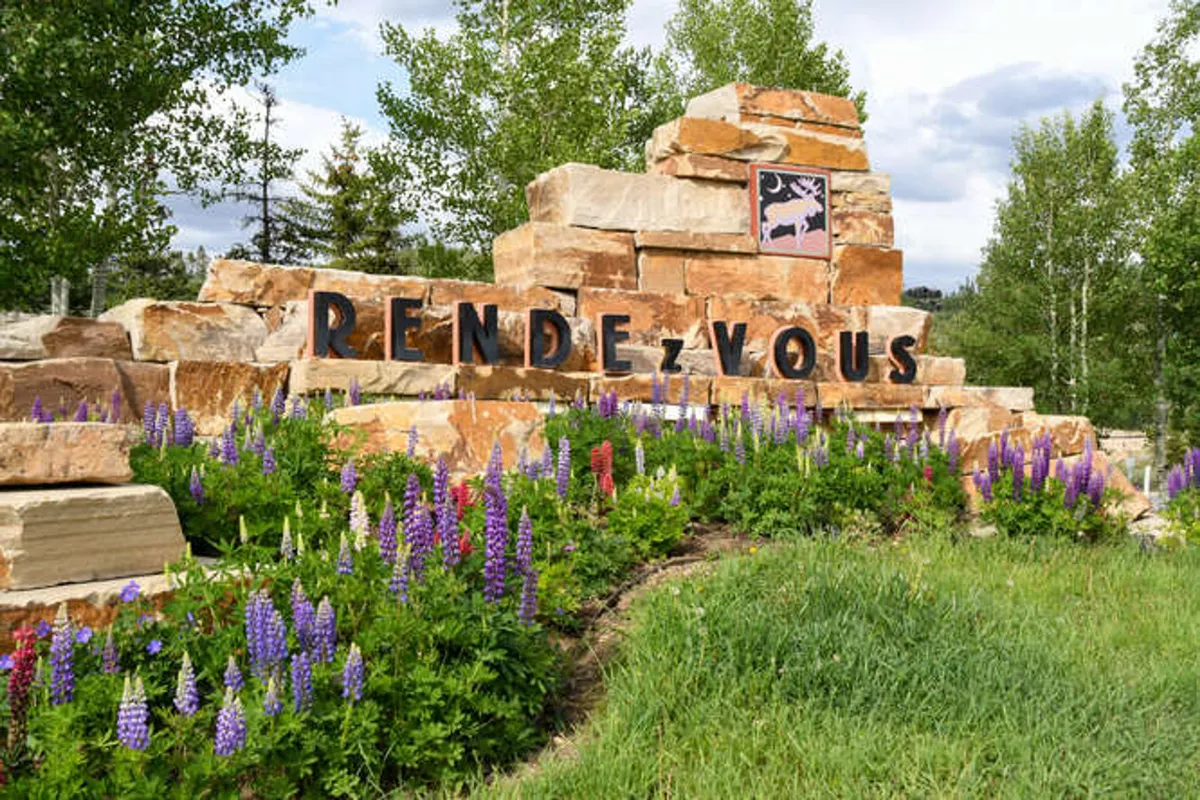 An exterior shot of a stone sign surrounded by vibrant flowers and lush green grass, evoking a sense of welcome and natural beauty. The scene suggests leisurely exploration, photography, and serves as a landmark for the community, possibly near event spaces or local attractions.
