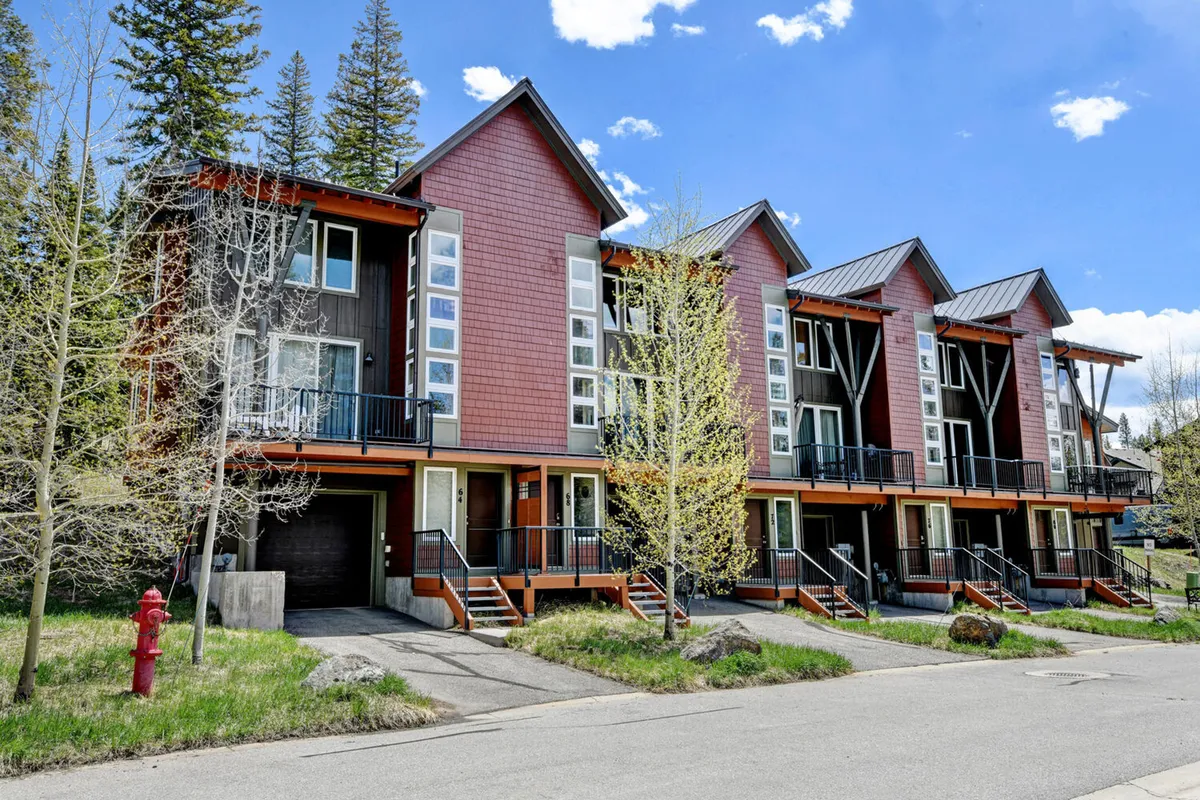 A view of modern architecture with colorful facades set against a backdrop of trees. The exterior setting includes balconies and communal outdoor spaces, suggesting opportunities for gatherings, barbecues, and neighborhood events. The scene is welcoming and hints at both residential comfort and active community life.